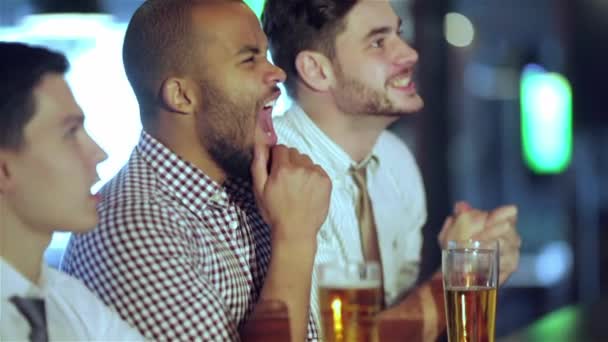 四个朋友商人喝着啤酒 在酒吧里一起看电视 欢欣鼓舞 一起大喊大叫 成功的商人朋友在酒吧里玩得很开心 在电视上喝啤酒看足球 — 图库视频影像
