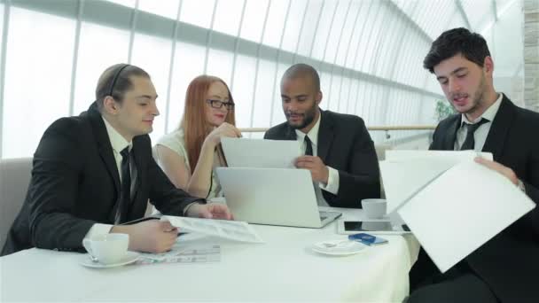 微笑的商人在一次会议上 与同事的商务会议 四个微笑的成功商人坐在办公室的桌子 — 图库视频影像