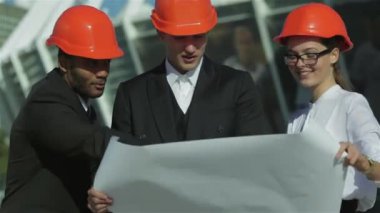 Üç emin iş koruyucu kask ayakta sitede mimar ve nesneyi görüntüleme. En iyi fikirler bina.