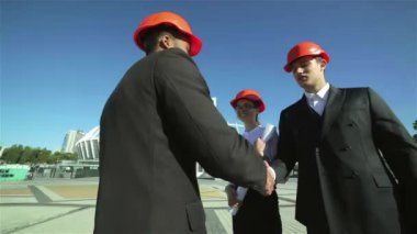 Üç emin iş koruyucu kask ayakta sitede mimar ve nesneyi görüntüleme. En iyi fikirler bina.