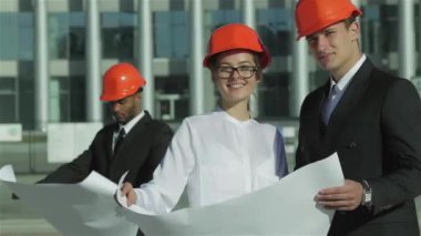 Üç emin iş koruyucu kask ayakta sitede mimar ve nesneyi görüntüleme. En iyi fikirler bina.