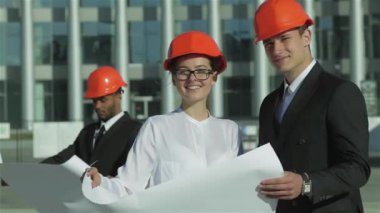 Üç emin iş koruyucu kask ayakta sitede mimar ve nesneyi görüntüleme. En iyi fikirler bina.