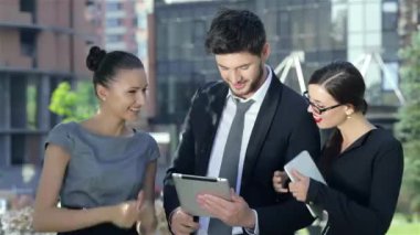 Üç başarılı iş adamı ofisin dışında ve kameraya gülümsüyorlar.