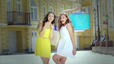 Kızlar alışveriş tutan çantalar ve dükkan yürümek. Gülümseyen kız birlikte eğleniyor.