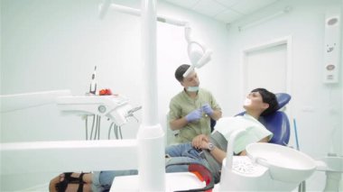 Genç profesyonel diş hekimi diş incelenmesi başlar. Hastanın dişleri denetler