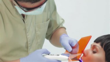 Ultraviyole fotopolimer mühür kullanarak dişçi. Yan görünümü. Diş hekimi düzeltmeleri mühür ultraviyole lamba. Diş hekimi tedavi güzel bir genç kızın işlemi yapar