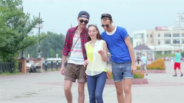 年轻的朋友们一起在街和微笑愉快地相互对视 愉快的一天生活的三个朋友 — 图库视频影像