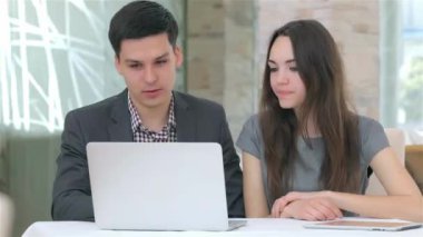 Genç çekici iş erkek ve kadın dizüstü bilgisayardaki verileri karşılaştırarak tartışıyor
