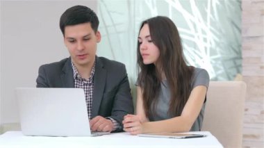 Genç çekici iş erkek ve kadın dizüstü bilgisayardaki verileri karşılaştırarak tartışıyor