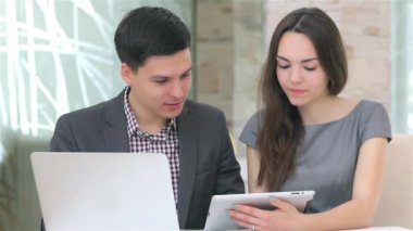 Genç çekici iş erkek ve kadın harmanlama veri tablet üzerinde tartışıyor