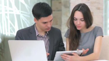 Genç çekici iş erkek ve kadın harmanlama veri tablet üzerinde tartışıyor