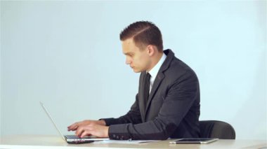 Genç işadamı laptop verileri toplar ve sonra o uzakta ve kameraya gülümseyen döner