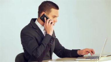 Genç işadamı çağrıyı yanıtlar sonra bir cep telefonu masanın üzerine koyar