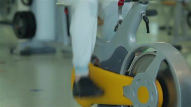 Genç adam bir sabit Bisiklet bacaklar için egzersiz yapmak