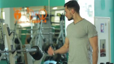 Genç adam ayna seyir dumbbells ile bir program yapıyor