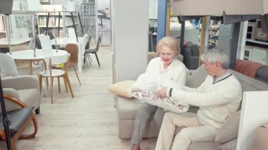 Neşeli yaşlı bir çift, parlak bir mağazada şık mobilyalar ve yumuşak yastıklarla çevrili lüks bir kanepede bir araya toplanıyor. Kahkahaları havayı dolduruyor.