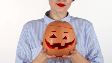 Kırmızı dudakları çarpan neşeli bir kadın kameraya doğru oyulmuş bir Cadılar Bayramı balkabağı tutuyor. Bu canlı sahne, sonbahar şenliklerinin özünü yansıtıyor.