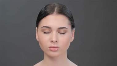 Çekici bir yakın plan, güzel bir Asyalı kadını yavaş yavaş gözlerini açarken yakalar ve sakin bir ifadeyi ortaya çıkarır. Düz, esmer saçları zarif bir şekilde toplanmış.