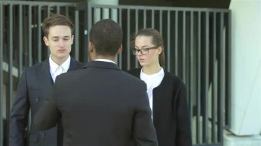 Resmi giyinmiş güler yüzlü iş adamlarından oluşan dinamik bir grup, hareketli bir şehir caddesinde sıcak bir tokalaşma, güven ve dostluk içinde el sıkışırlar. Bu hareketli sahne,