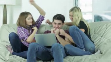 Üç neşeli arkadaş şen şakrak bir şekilde lüks bir koltukta bir adama sarılıyor, mutluluk ve dostluk saçıyor. Kahkahalar havayı doldurur birlikte eğlenceli bir anın tadını çıkarırlarken, etrafları aydınlık