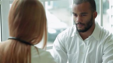 Nazik bir doktor, parlak ve modern bir klinikte ameliyat seçeneklerini tartışan düşünceli bir yüz ifadesi olan hastasını dikkatle dinler. Sıcak atmosfer doktor tarafından arttırılır.