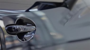 Yeni başlangıçların heyecanını sembolize ederek lüks bir arabanın kapısını açan iyi giyimli bir erkek elinin yakın çekimi. Bu dinamik an, otomobil endüstrisinin özünü yakalar.