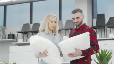Kameraya neşe saçan bir çift, şık mobilya dükkanını keşfederken kabarık yastıkları kucaklıyor. Bu hoş sahne yeni evlilerin özünü yakalıyor. Keyifli bir şekilde evlerini düzenliyorlar.