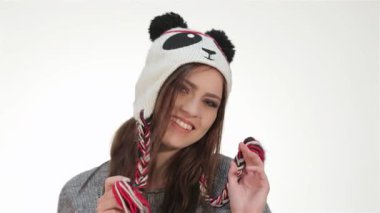 Bu canlı portre neşeli bir genç kızın neşeli bir panda şapkasıyla neşeli bir şekilde poz verişini çekiyor, neşe ve enerji saçıyor. Parlak gülüşü ve canlı ifadesi beyaz bir arkaplan yaratıyor.