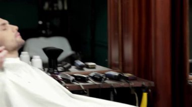 Şık bir berber dükkanında, yetenekli bir berber müşterisinin sakalını titizlikle tıraş eder, hassas ve sanatsal özelliklerini sergiler. Kaliteli dekor ve yumuşak ışıklandırmayla vurgulanan ılık ortam, tımarı geliştirir.