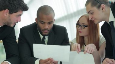 Bir kadın da dahil olmak üzere kendinden emin dört işadamından oluşan bir grup, belgelerini analiz ederek ve şık bir ofis ortamında fikirlerini paylaşarak ateşli bir tartışmaya girişiyor. Gülümsemeleri ve odaklanmaları