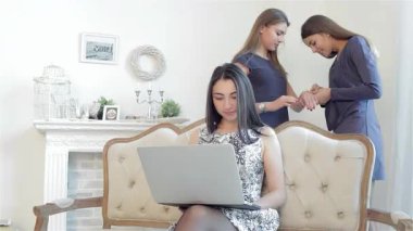 Üç modaya uygun kız arkadaş hoş bir online alışveriş seansının keyfini çıkarırken, bir tanesi şık bir dizüstü bilgisayarda gezinirken, diğerleri de şık bulgularını heyecanlı bir şekilde tartışıyor. Zarif bir dekorla süslenmiş, sıcak ve dostça bir ortam.