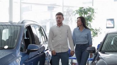 Şık bir çift galeride parlak mavi bir SUV 'ye yaklaşırken, çekici adam kız arkadaşına hareketli bir şekilde özelliklerini anlatıyor. Güzel esmer kadın, bu heyecan verici arabayı paylaşırken şefkatle omzuna yaslanıyor ve mutluluk saçıyor.