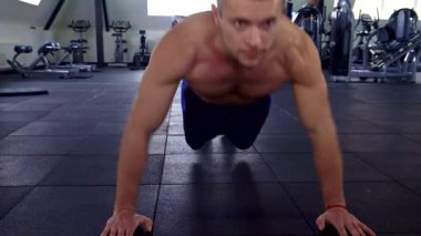 Odaklanmış beyaz bir atlet şık bir spor salonunda etkileyici fiziğini sergileyerek şınav çekiyor. Kamera sorunsuzca süzülüyor, modern bir fitness merkezinde güç ve güç kazanırken gözlerindeki kararlılığı yakalıyor.