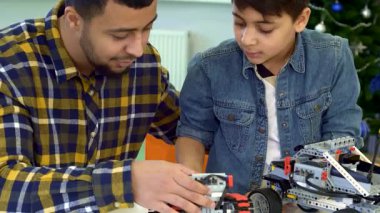 Çekici bir baba ve küçük esmer oğlu bir festival masasında ATV 'nin izini süren bir oyuncağı keşfetmeye çalışıyorlar. Genç Afrikalı Amerikalı adam, oyuncak konsolundaki düğmelere hevesle basan çocuğuyla kahkahaları paylaşıyor.