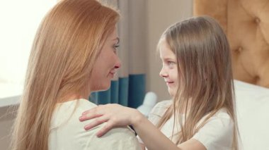 Sevimli küçük bir kız, kollarını annesine sarıyor, gözleri bir anlık saf aşkla kapanıyor. Bu iç açıcı sahne aile sevgisinin özünü yakalar, anne ve kız arasındaki derin bağı gözler önüne serer.
