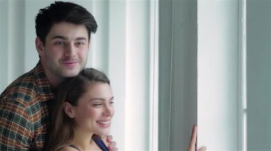 Neşeli bir çift pencerenin kenarında durur, taşınan kutularla çevrili, yeni yolculuklarına çıkarken sevgi ve heyecan saçan bir çift. Gülüşleri, sonsuz boş bir dairede yeni bir başlangıç yapmanın mutluluğunu yansıtıyor.