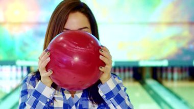 Uzun esmer, çekici, beyaz bir kadın yüzünü parlak kırmızı bir bowling topunun arkasına saklar. Eğlenceli ve heyecanlı bir hava yayar. Renkli bovling salonu, canlı atmosferi yükselterek izleyicileri katılmaya davet ediyor.