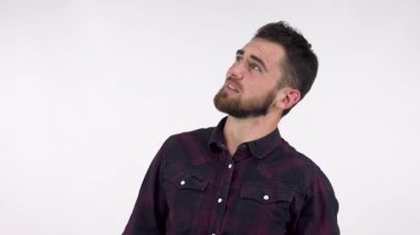 Yakışıklı sakallı bir adam, kulaklarını kapatırken yüzünü buruşturur ve kendini kahpelikten korumaya çalışır. Bu çarpıcı görüntü, kargaşanın ortasında huzuru bulma mücadelesini gösteren endişe ve stresin özünü yakalıyor.