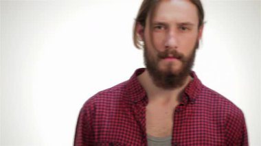 Çekici, bakımlı sakallı ve uzun saçlı genç bir hippi çağdaş stüdyo ortamında rahatça poz veriyor. Ekose gömleği ve ciddi ifadesi havalı, modern bir hava yayıyor. Yaşam tarzı ve moda teması için mükemmel.