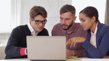 İki beyaz erkek ve bir siyah kadından oluşan dinamik bir üçlü şık bir ofis masasında canlı bir beyin fırtınası yapıyorlar. Afro-Amerikan kadın özgüvenli bir şekilde dizüstü bilgisayarı işaret ederken sakallı adam da fikirlerini not alıyor.