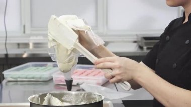 Hareketli bir mutfakta, yetenekli bir şekerci bir pasta poşetini lezzetli bir tatlı oluşumuna hazırlanan kremalı ekşi kremayla güzelce doldurur. Sahne, aşçılık sanatının özünü yakalıyor. Arkasındaki hassasiyet ve tutkuyu gözler önüne seriyor.