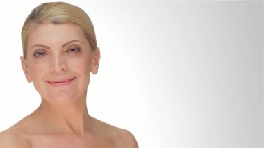 Bu büyüleyici portre orta yaşlı, gülümseyen, pırıl pırıl, pürüzsüz bir cilde sahip, yumuşak, eğimli beyaz bir arkaplanı olan bir kadını gösteriyor. Onun nazik ifadesi ve doğal güzelliği cilt bakımının özünü vurguluyor, izleyicileri kendilerini kucaklamaya çağırıyor.