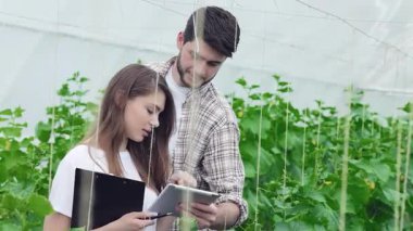 Berrak bir serada, genç bir adam her ikisi de ziraatçi olan genç bir kadına tablette sağlıklı bitki örnekleri sunar. Canlı yeşil ekinlerle çevrelenmiş, modern çiftçiliğin ruhunu somutlaştırıyorlar, organik tutkularını sergiliyorlar.