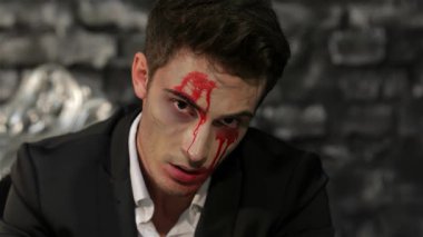 Büyüleyici bir vampir adam ruhuna bakıyor, yüzü gölgeli tuğla bir duvara karşı dramatik kan çizgileriyle bezenmiş. Bu çarpıcı görüntü Cadılar Bayramı 'nın özünü somutlaştırıyor, cazibe ve korkuyu ürpertici ama büyüleyici bir şekilde harmanlıyor.