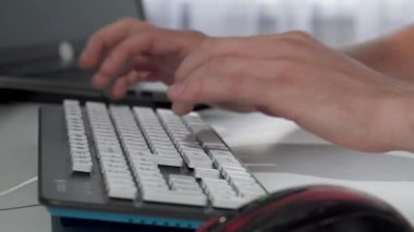 Modern bir klavyeye ustalıkla yazı yazan, üretkenlik ve yaratıcılığın özünü somutlaştıran bir adamın yakın çekimi. Bu dinamik sahne, teknolojiye dalmış bir serbest çalışanın enerjisini yakalıyor ve insanlar arasındaki kusursuz bağlantıyı gösteriyor.