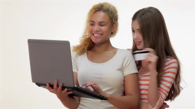 Biri kıvırcık sarı saçlı, diğeri uzun kahverengi saçlı iki neşeli kız internetten alışveriş yapıyorlar. Dizüstü bilgisayardan eşyalar seçmekle meşguller. Arkadaşlıklarını ve heyecanlarını parlak, minimalist bir ortamda sergiliyorlar.