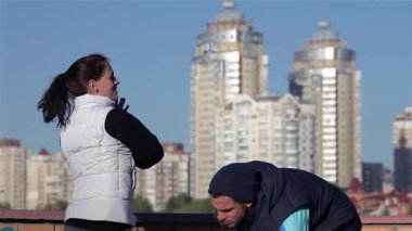 Dinamik ikili sabah koşularına hazırlanıyor. Parlak gökdelenlerin çarpıcı şehir zeminine doğru geriliyor. Bu canlı sahne fitness ve yoldaşlığın özünü yakalıyor, açık hava tatbikatının neşesini sergiliyor.