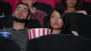 Neşeli bir çift sinema koltuklarında oturur, büyük ekrandaki film karşısında büyülenirler, etrafları film izleyicileriyle çevrilidir. Patlamış mısır ve gazoz paylaşırken ortam heyecanla dolup taşıyor. Bu da sinemada geçirdikleri gecenin neşesini simgeliyor.