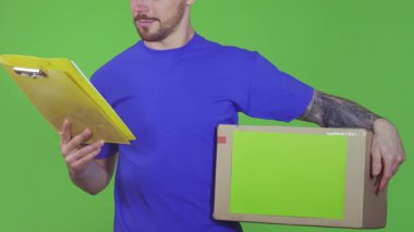 Dost canlısı bir gülümsemesi olan canlı bir teslimatçı canlı yeşil bir zemine karşı bir pano ve bir karton kutu sunar. Bu ilgi çekici sahne, teslimat servisindeki profesyonellik ve adanmışlığın özünü yansıtıyor.