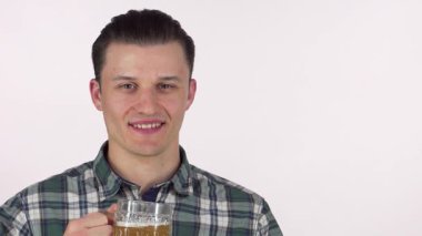 Neşeli, neşeli bir gülümsemesi olan genç bir adam şenlik ruhunu somutlaştıran köpüklü bir kupa biranın tadını çıkarıyor. Ekose gömleği bu anı hafta sonu kutlamaları ve toplantılar için mükemmel kılıyor.